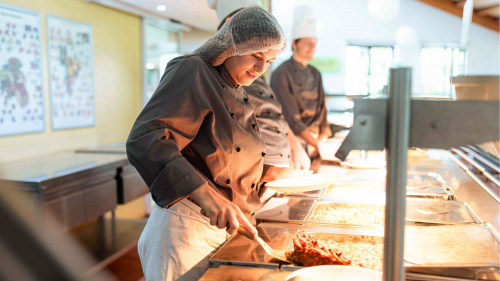 Auszubildende an der Theke bei der Essensausgabe.