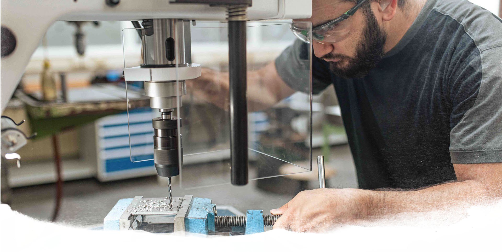 Lernen in der Paulinenpflege, Ausbildung, Metallbau Auszubildender mit Hörgerät arbeitet in der Werkstatt an einer Stand-Bohrmaschine