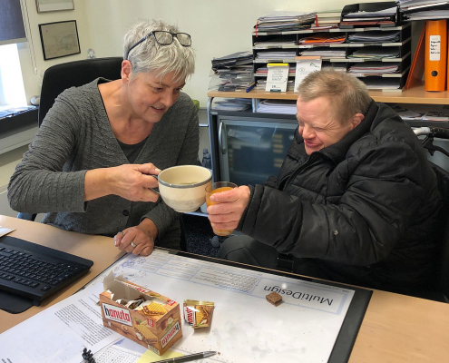 Susanne Gebert-Ballmann und behinderter Mann stoßen mit Tee und Saft auf alte Zeiten an