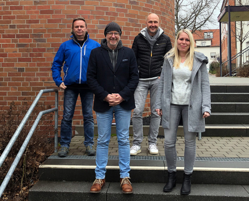 Das LUT-Leitungsteam, drei Männer und eine Frau, stehen auf einer Außen-Treppe