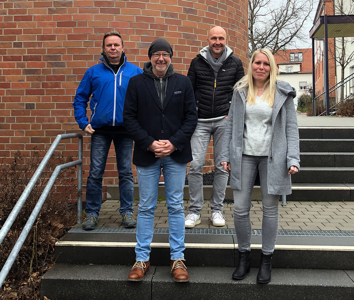 Das LUT-Leitungsteam, drei Männer und eine Frau, stehen auf einer Außen-Treppe