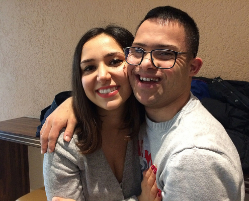 Junger Mann mit Down-Syndrom umarmt junge Frau