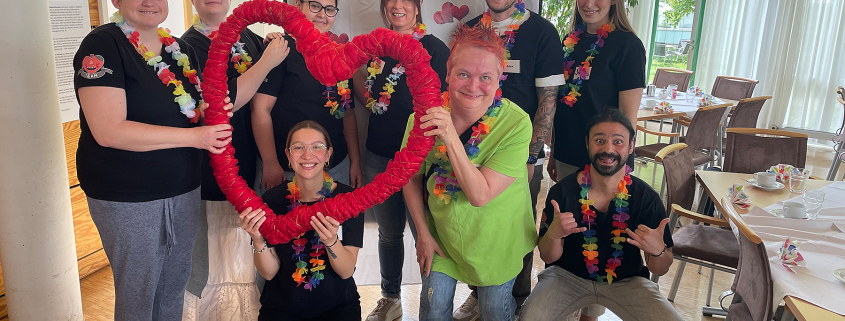 Das Herz-Café-Team hält ein großes Herz hoch