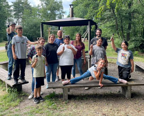 Jugendgruppe der Erlebnispädagogik vor einem Grillplatz im Wald