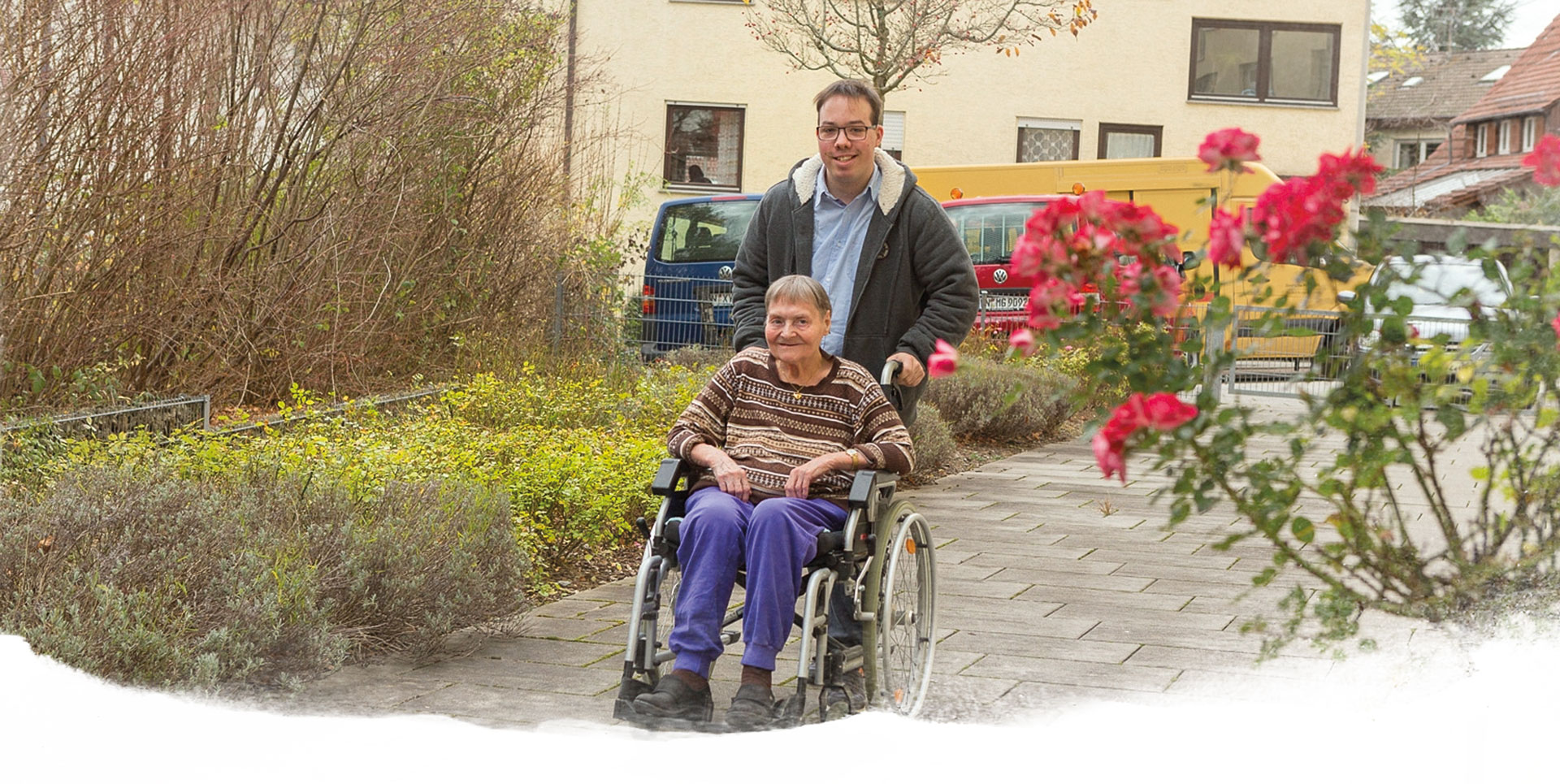Lernen in der Paulinenpflege, Berufsfachschule für Sozialpflege, Alltagsbetreuer Junger Mann schiebt den Rollstuhl einer älteren Frau beim Spazieren gehen