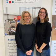 Zwei Frauen stehen vor einem Plakat der Backnanger Werkstätten.