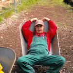 Ein junger Mann liegt in einer Schubkarre.