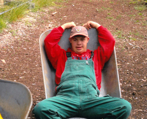 Ein junger Mann liegt in einer Schubkarre.