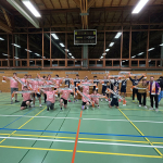 Gruppenbild mit allen Basketball-Spieler*innen mitten der Sporthalle.