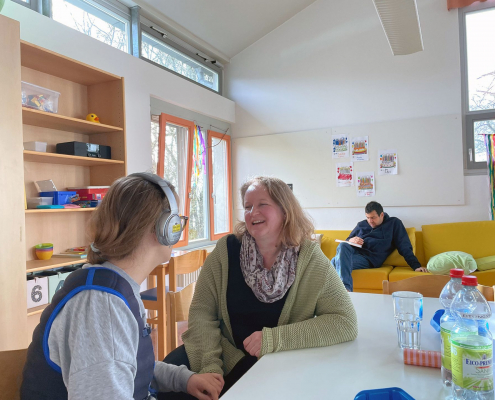 Eine Frau spricht mit einer anderen Frau, die einen Kopfhörer trägt.