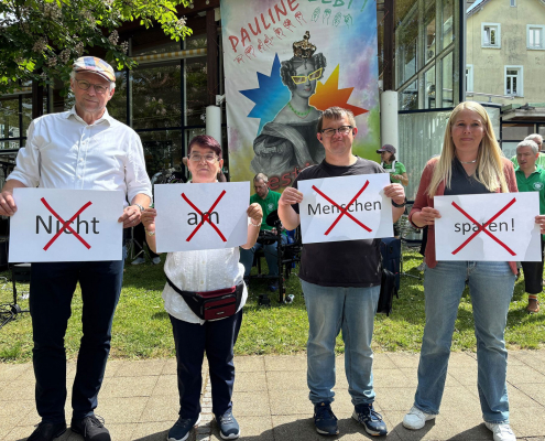 Vier Menschen mit Plakaten in der Hand: Nicht am Menschen sparen. Jedes Wort ist mit einem roten Kreuz durchgestrichen.