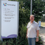 Ein Mann steht vor einem Paulinenpflege-Wegweiser des BBW Winnenden.