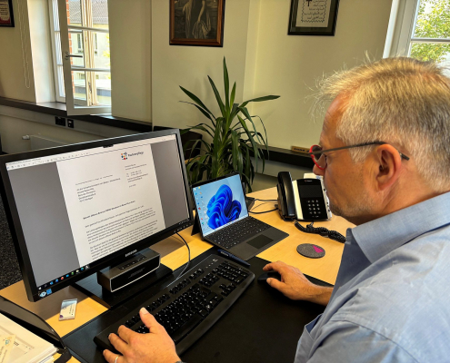 Ein Mann sitzt an einem Schreibtisch und schaut in seinen Computer-Bildschirm. Darauf ist der Offene Brief zu sehen.
