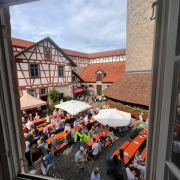 Blick aus dem Fenster auf Menschen, die auf Bierbänken sitzen.