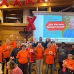 Der Bewohnerbeirat der Paulinenpflege steht auf der Bühne. Die Personen halten Postkarten mit "Nicht am Menschen sparen" in die Kamera.